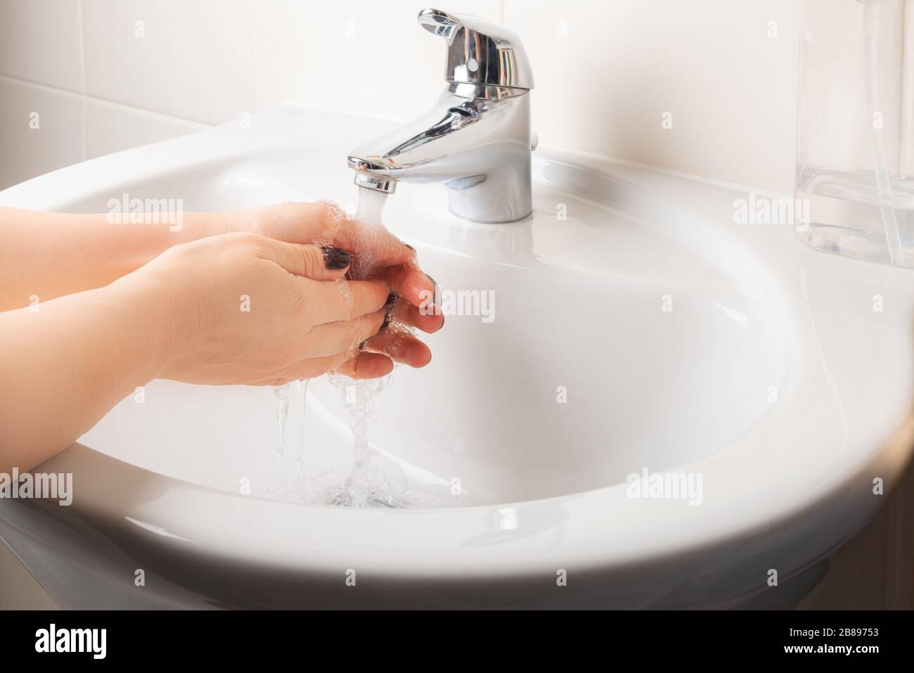 Woman is washing hands with soap under running water for 20 seconds ...