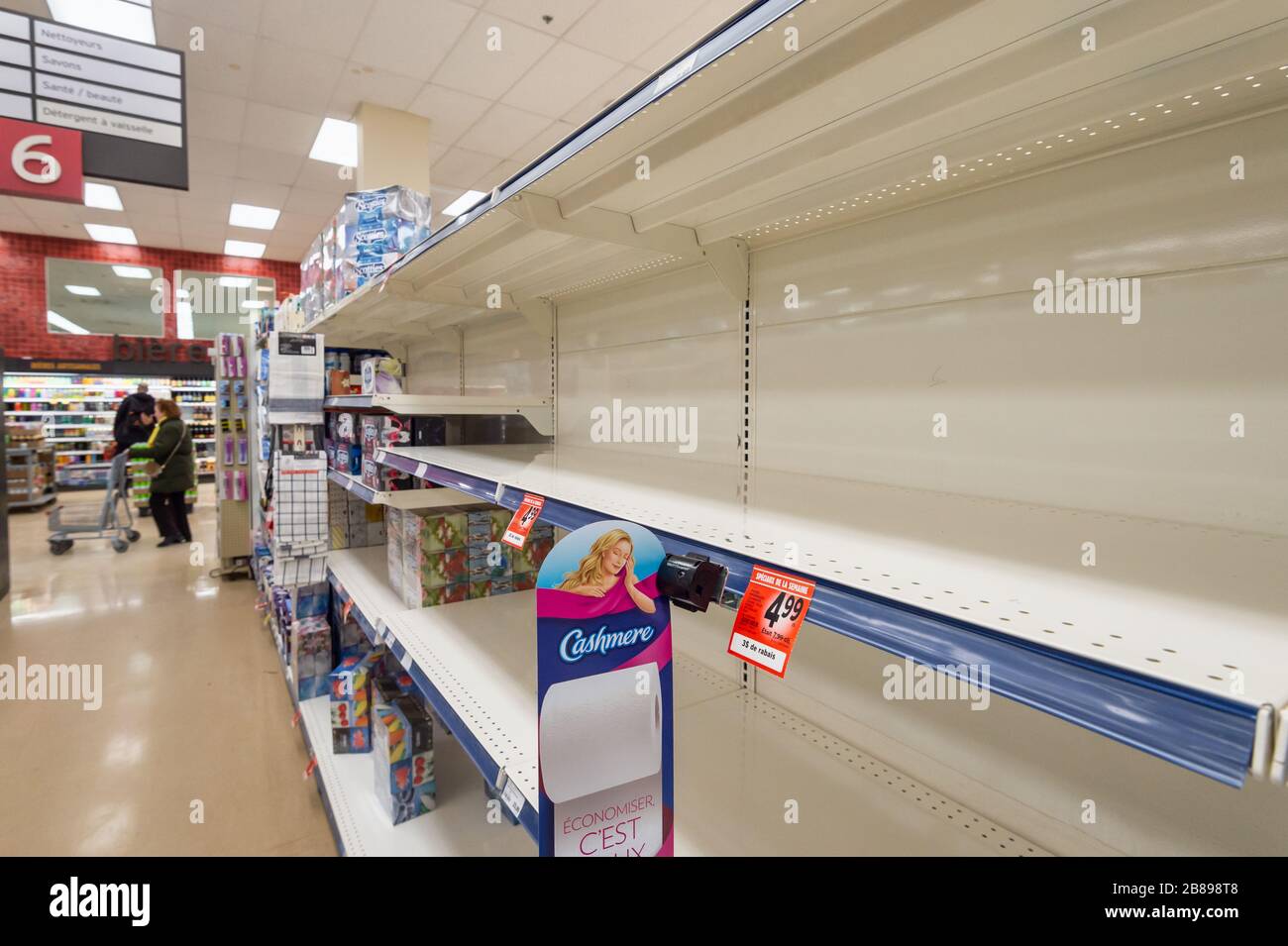 Montreal, CA - 20 March 2020: Empty shelves of toilet paper in a supermarket. Shortage of supplies due to panic of Coronavirus. Stock Photo
