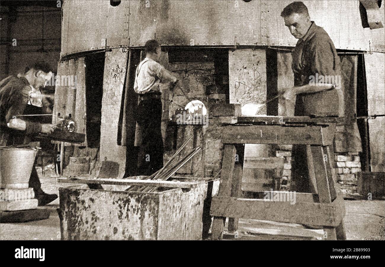 Men working in the old Stourbridge Crystal Glass Works (UK)  circa 1930s/ early 1940's -  This  old photograph of  lead crystal glass workers shows glass  being  marvered (right), shaped in a 'chair' (left) and 'gathered' (centre).  For around for 375 years glass was formerly made in  large quantities in an area stretching from Stourbridge in the south to Dudley in the north, having been started by 17th century  French immigrants from Lorraine Stock Photo