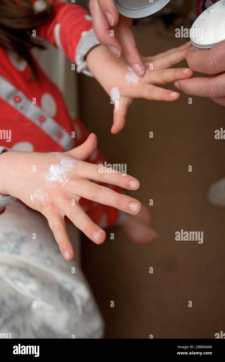 Applying hand lotion to dry over washed hands in response to Covid 19 Virus, uk Stock Photo