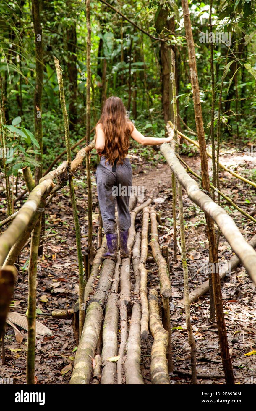 Girl crossing a Amazon log bridge.Peru, South America. Stock Photo
