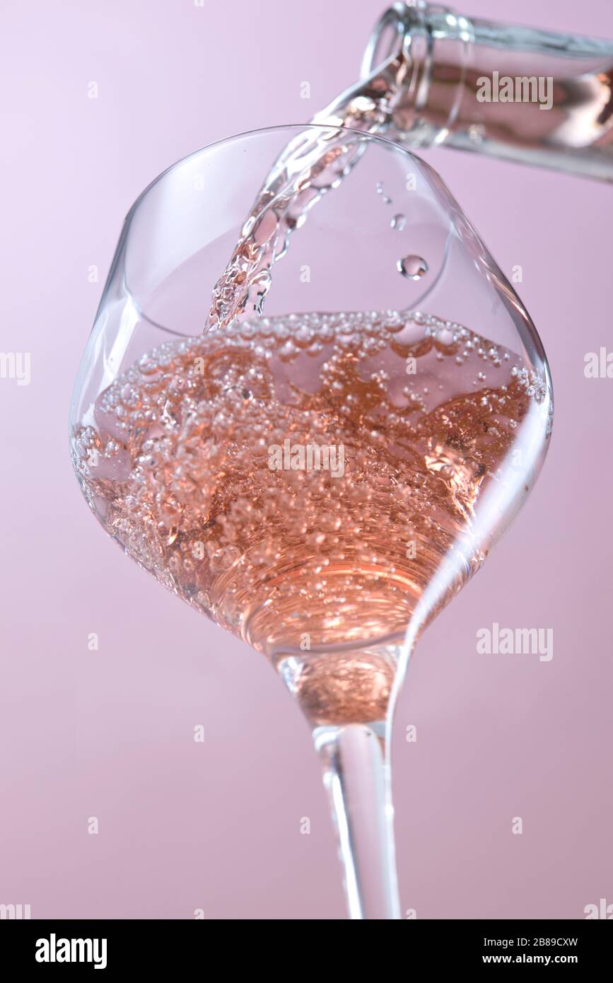 A concept studio image of pouring rose wine into a wine glass. Stock Photo