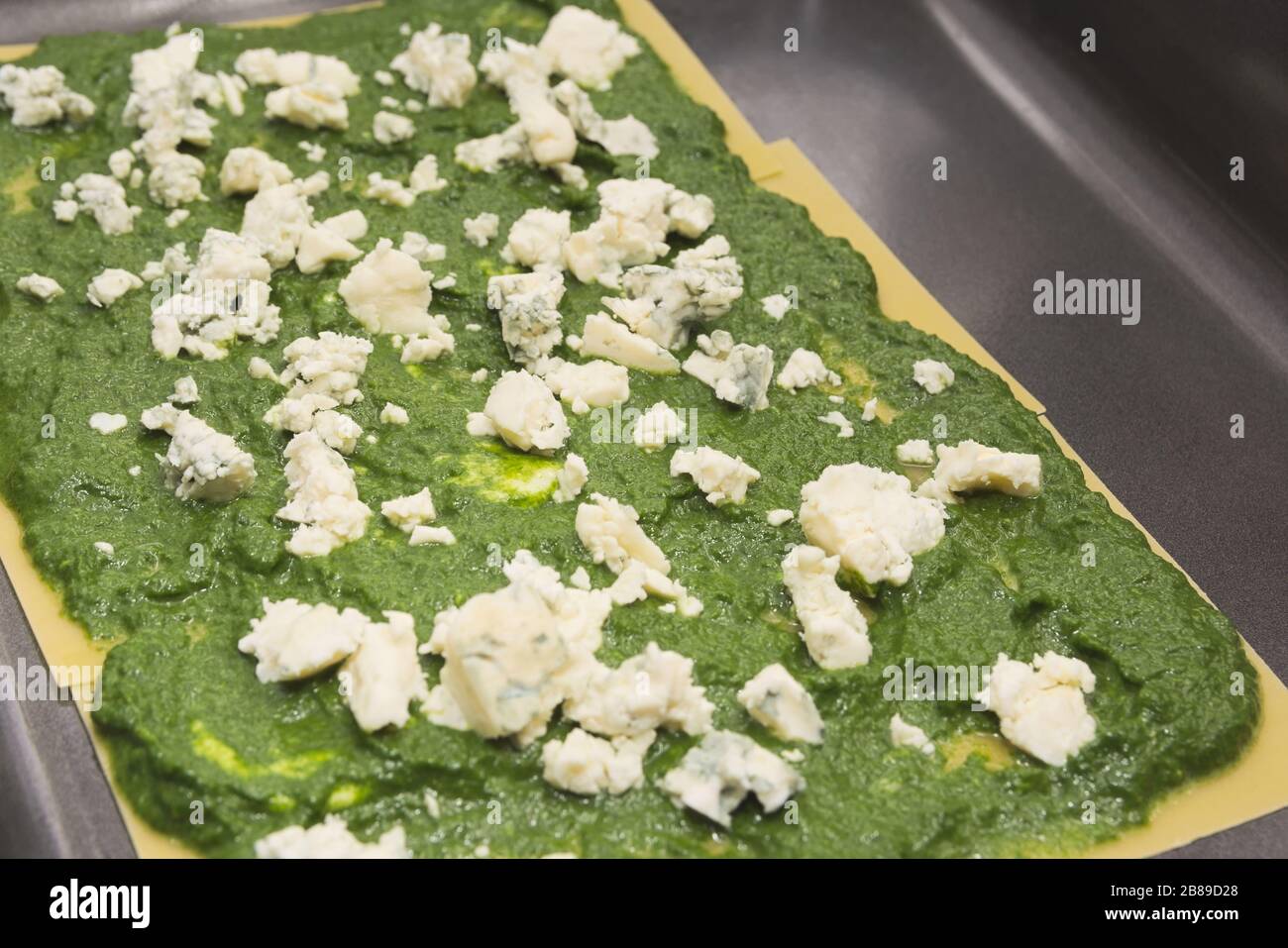 Spinach and Moldy Cheese on Raw Lasagne Pasta in Baking Sheet Stock Photo
