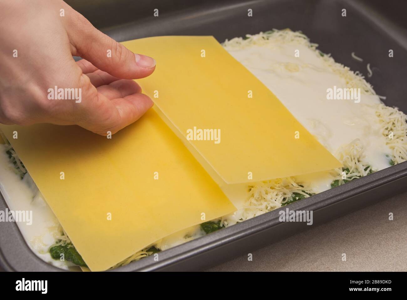 Housewife Hand Placing Raw Lasagne Pasta onto Baking Sheet Stock Photo
