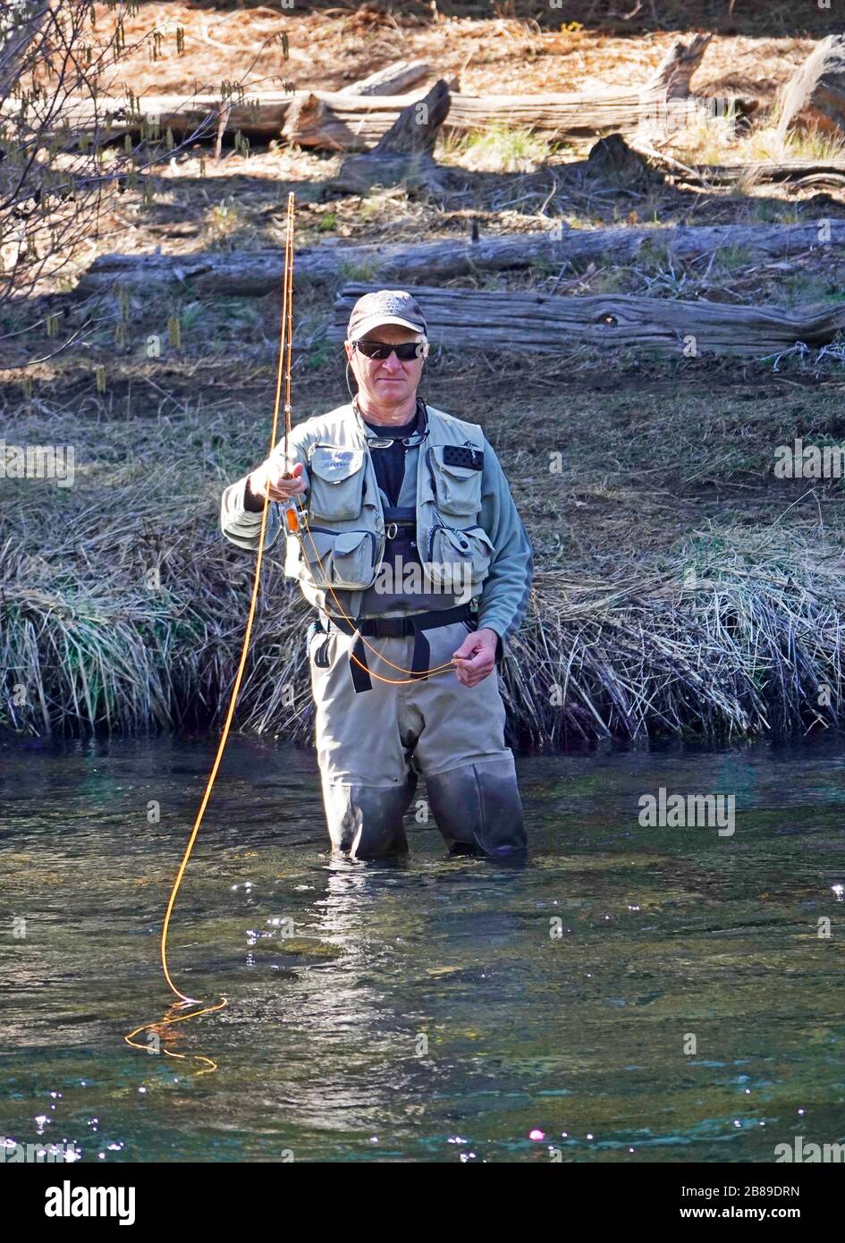 A fly fisherman fisherman casts for rainbow trout on the Metolius River in the Cascade Mountains of central Oregon. Stock Photo