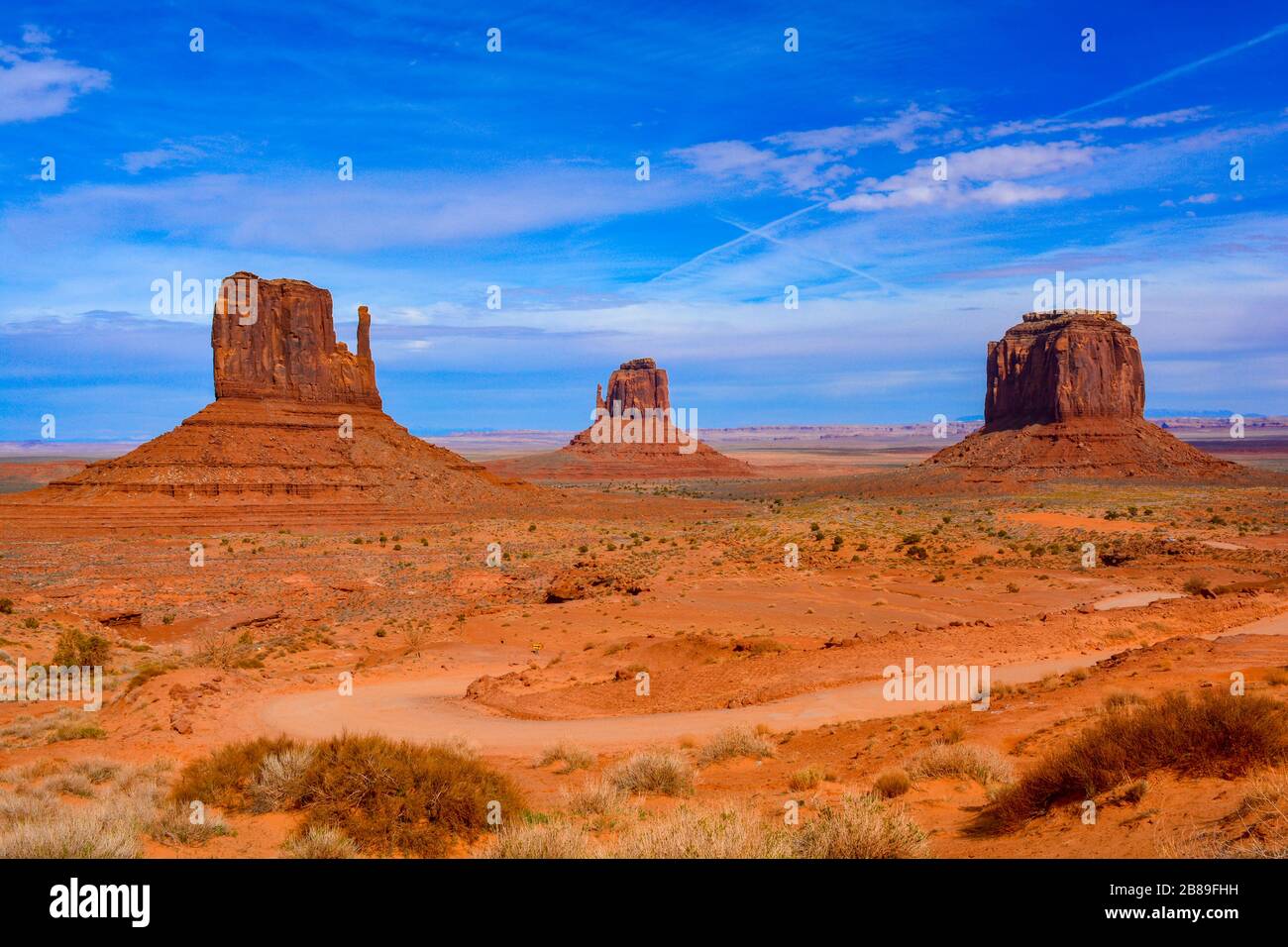Amazing iconic view of Monument Valley, Utah, Arizona, USA. The most famous buttes: West Mitten, East Mitten and Merrick under a blue limitless sky Stock Photo