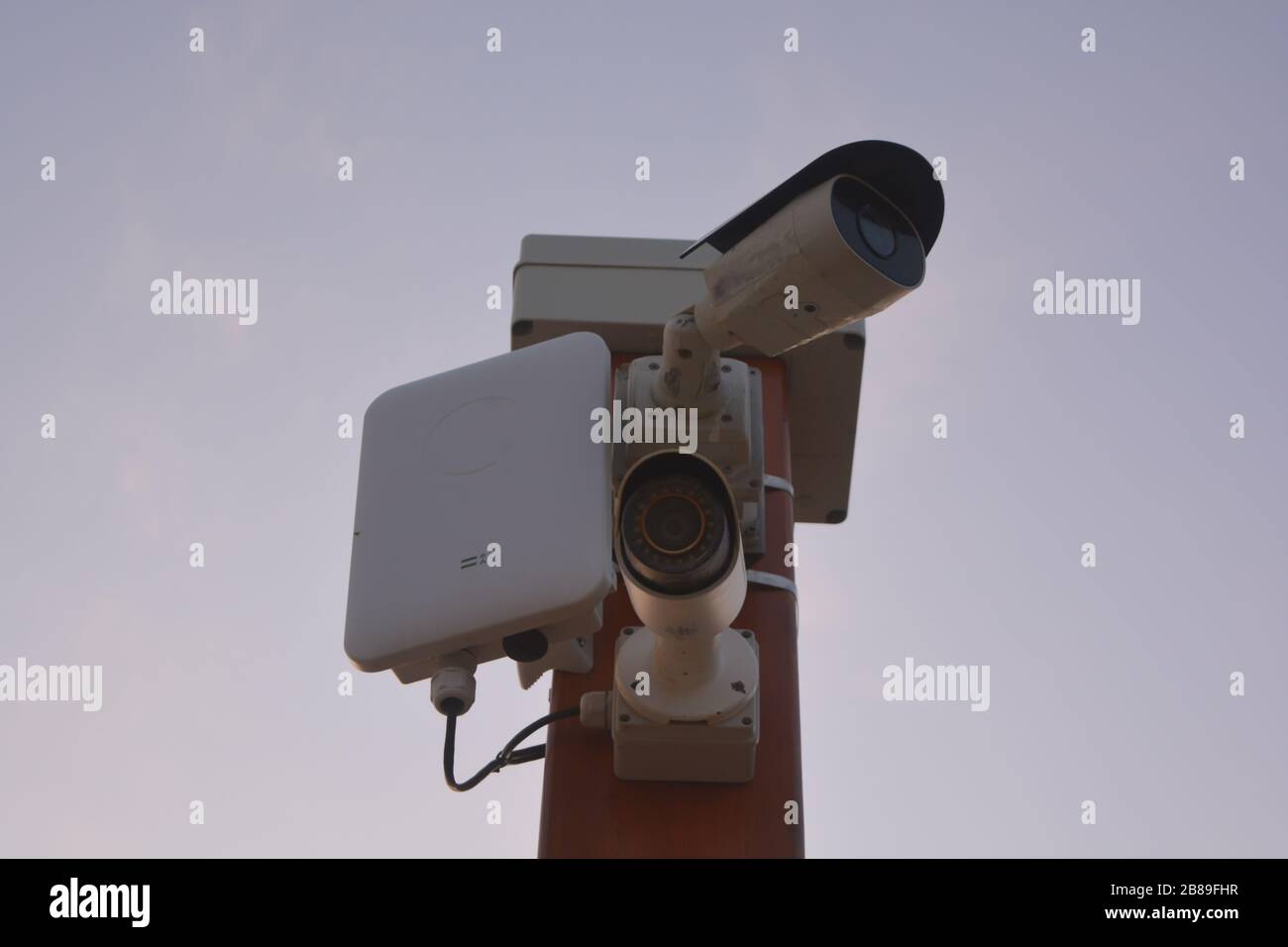 Two white security cameras (CCTV) record video for public safety and security. Advanced technological system that violates privacy and freedom spying Stock Photo