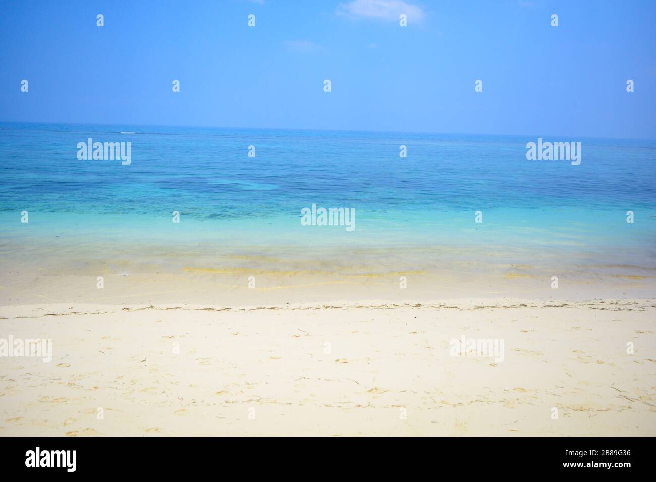 Idyllic view of turquoise sea and white fine sand beach.Tropical paradise background.Perfect day of sunshine in the cleanest empty beach.Limitless sky Stock Photo