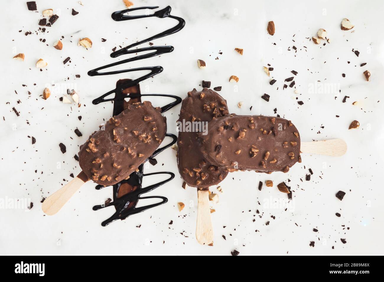 three ice cream bars on a white background, chocolate drizzle and nuts Stock Photo
