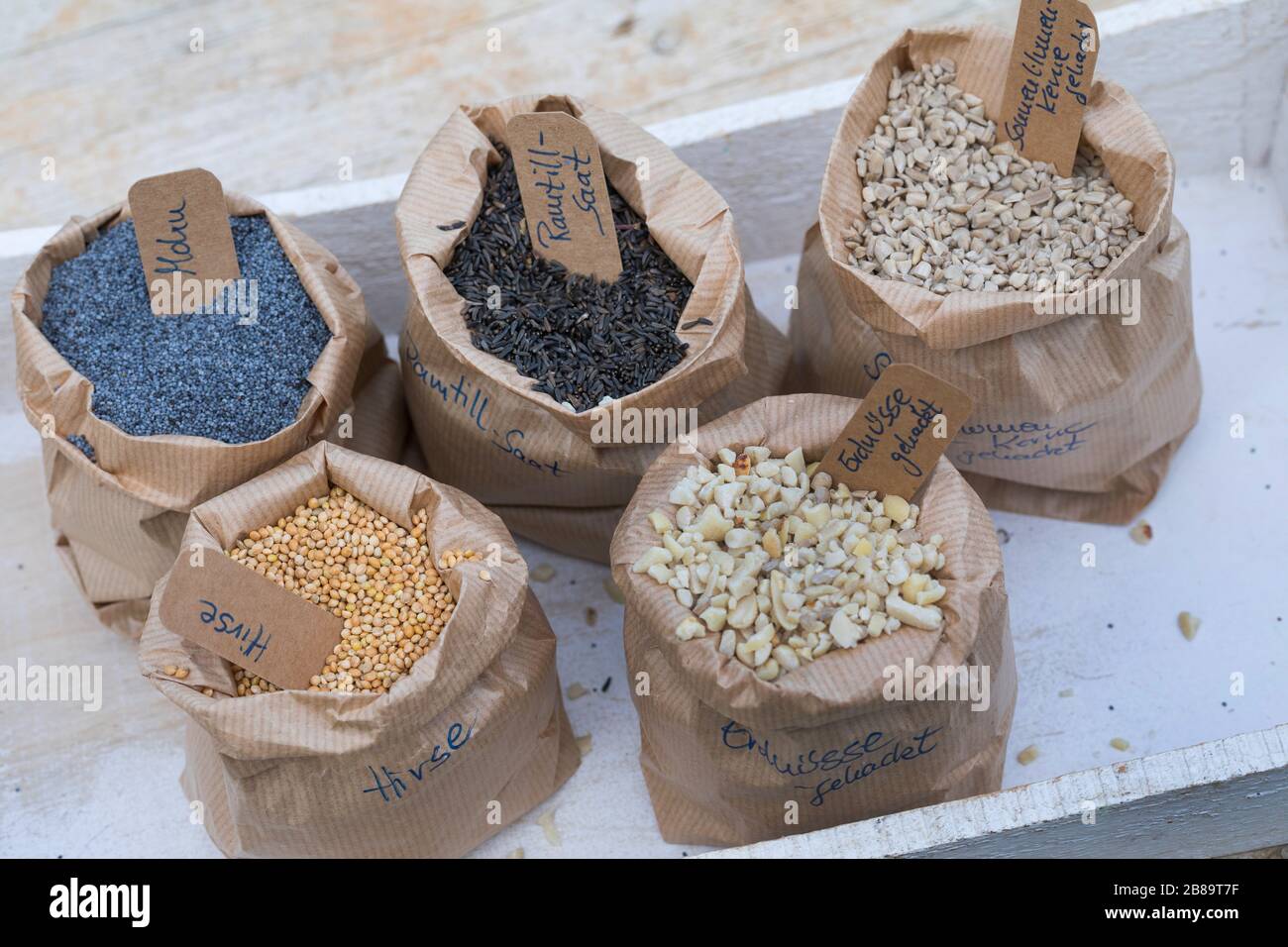 ingredients for mixed birdseeds: poppyseed, ramtil seed, sunflower seeds, millet and chopped peanuts, Germany Stock Photo