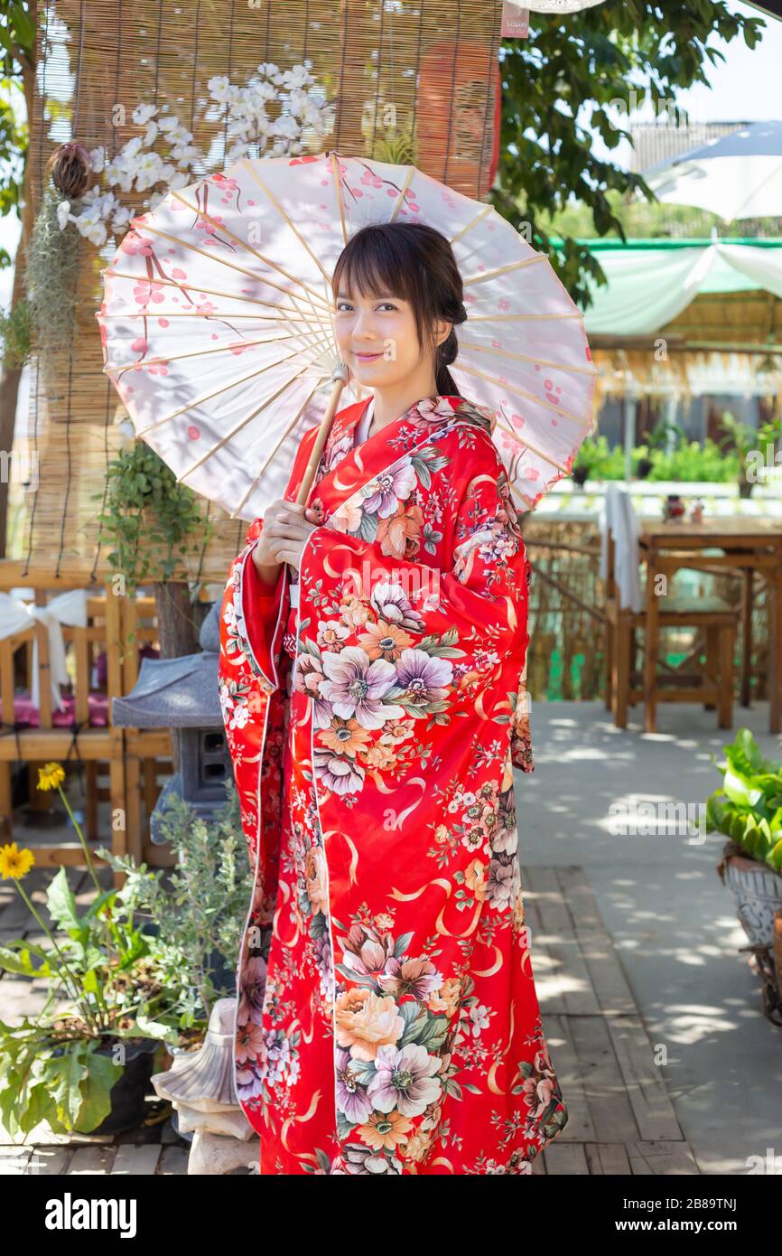 The girl is wearing a red traditional kimono, which is the national dress  of Japan and Hold an umbrella Stock Photo - Alamy