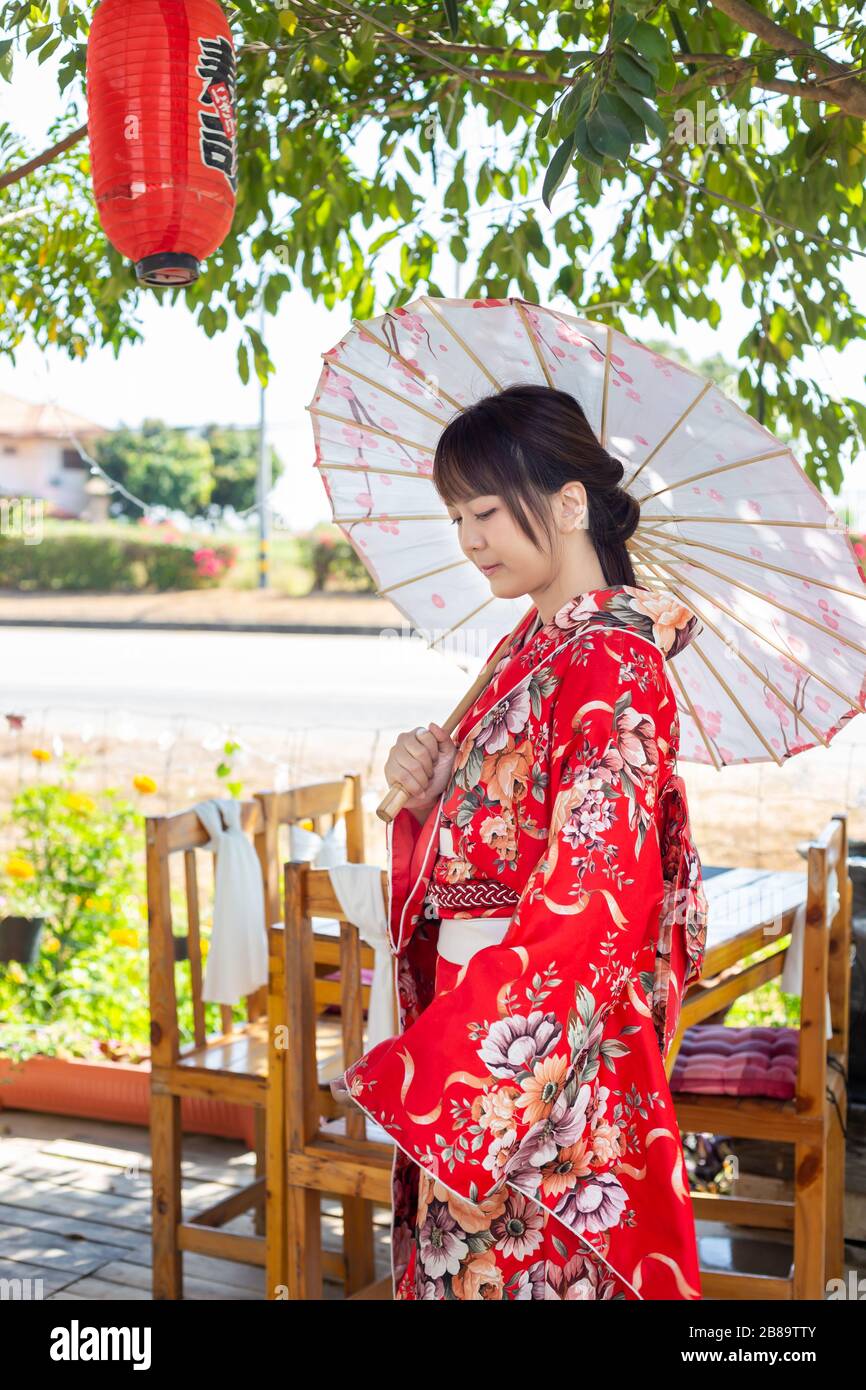 The girl is wearing a red traditional kimono, which is the national dress  of Japan and Hold an umbrella Stock Photo - Alamy