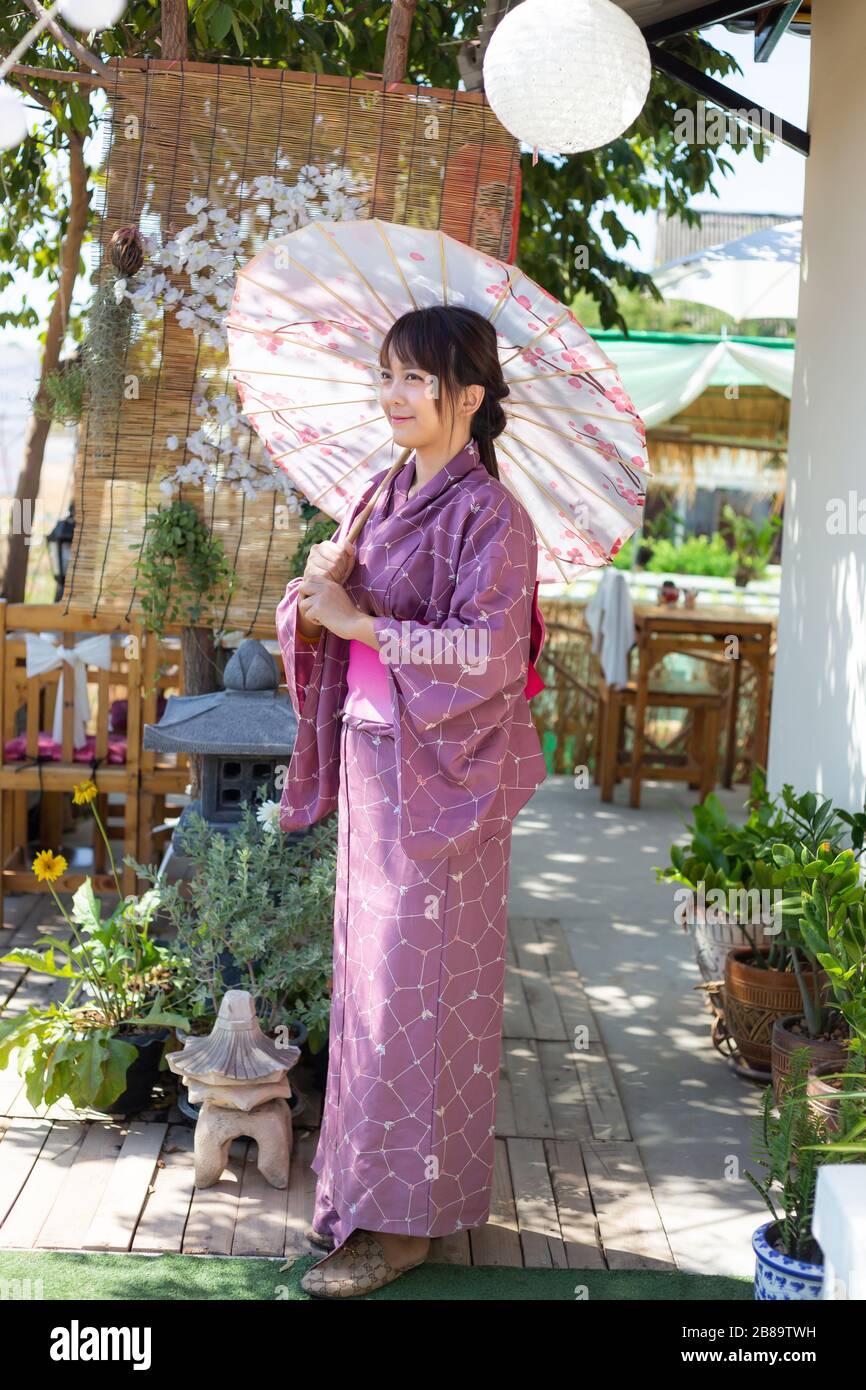 The girl is wearing a pink traditional yukata, which is the national dress of Japan and Hold an