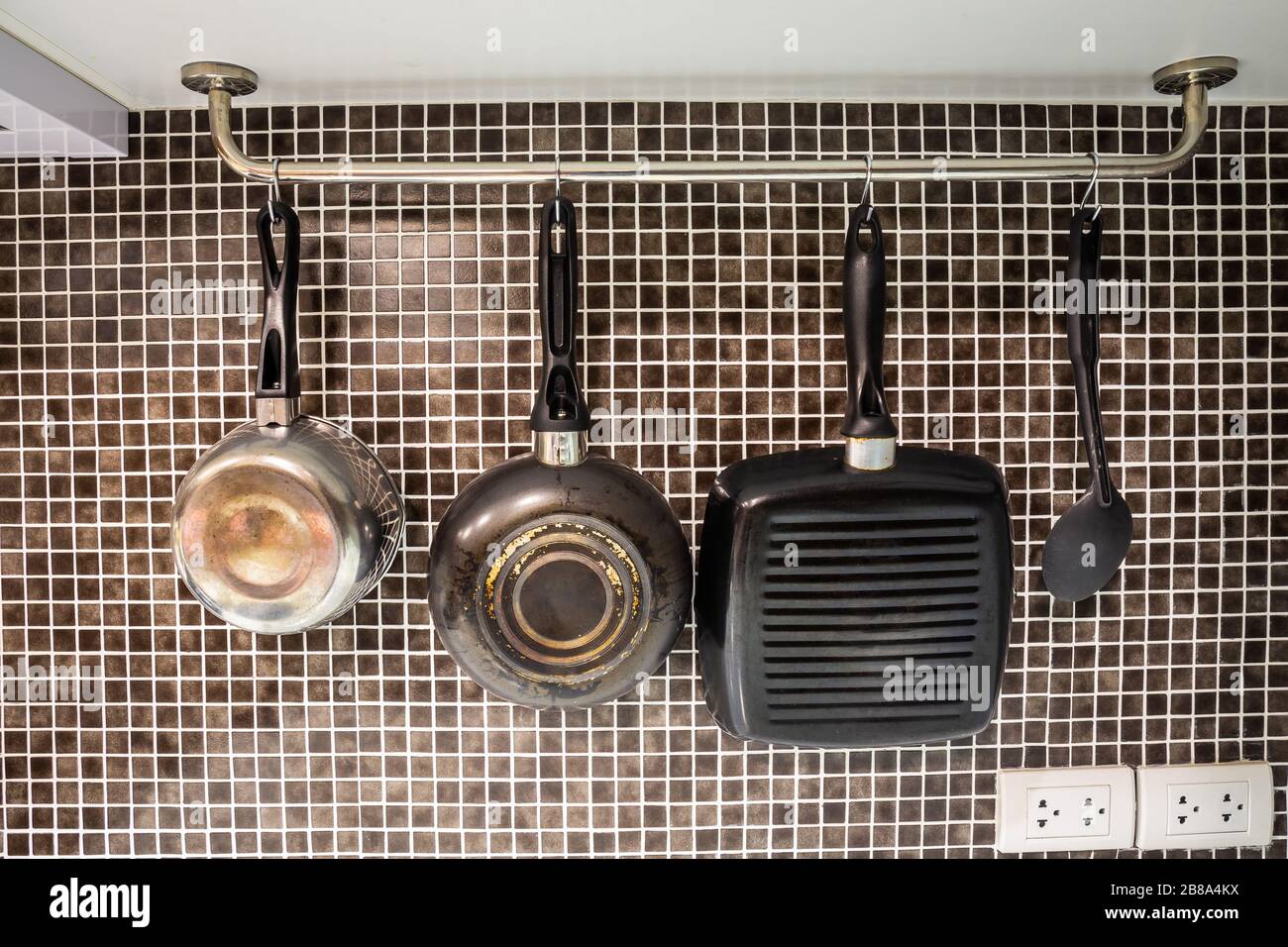 Pots and pans and ladle for cooking, hanging in the kitchen Stock Photo