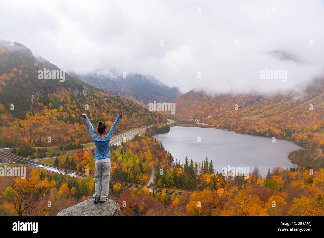 Woman posing in front of beautiful Echo Lake from Artists Bluff Loop in New Hampshire USA Stock Photo