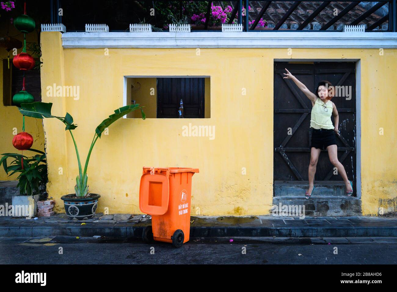 Tourist jumping in the doorway of a building in the heart of Hoi An, Vietnam Stock Photo