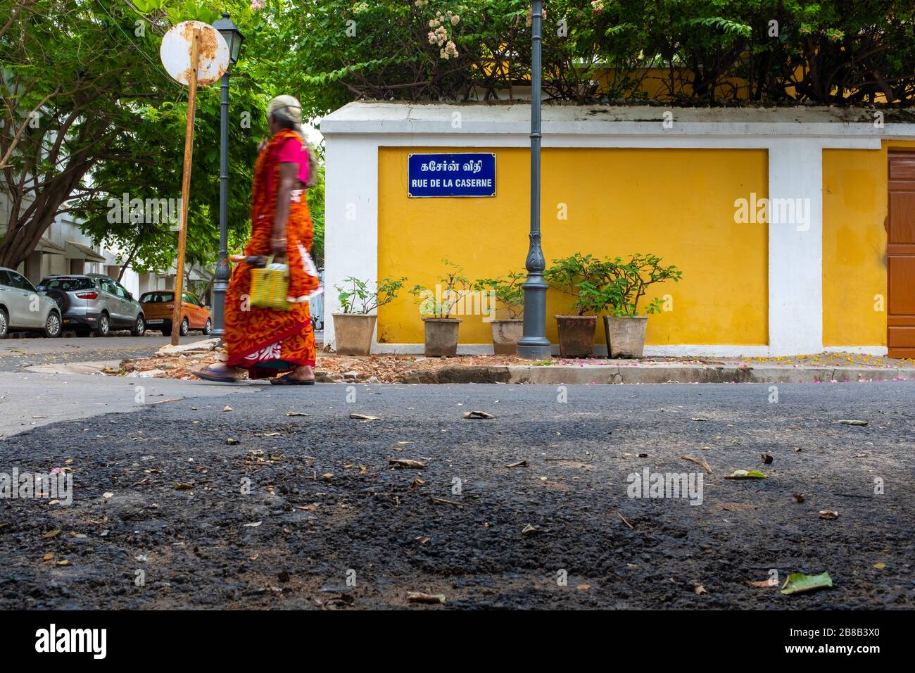 Pondicherry, India - March 19, 2018: Unrecognisable woman wearing bright colours is walking by a street sign in French Stock Photo