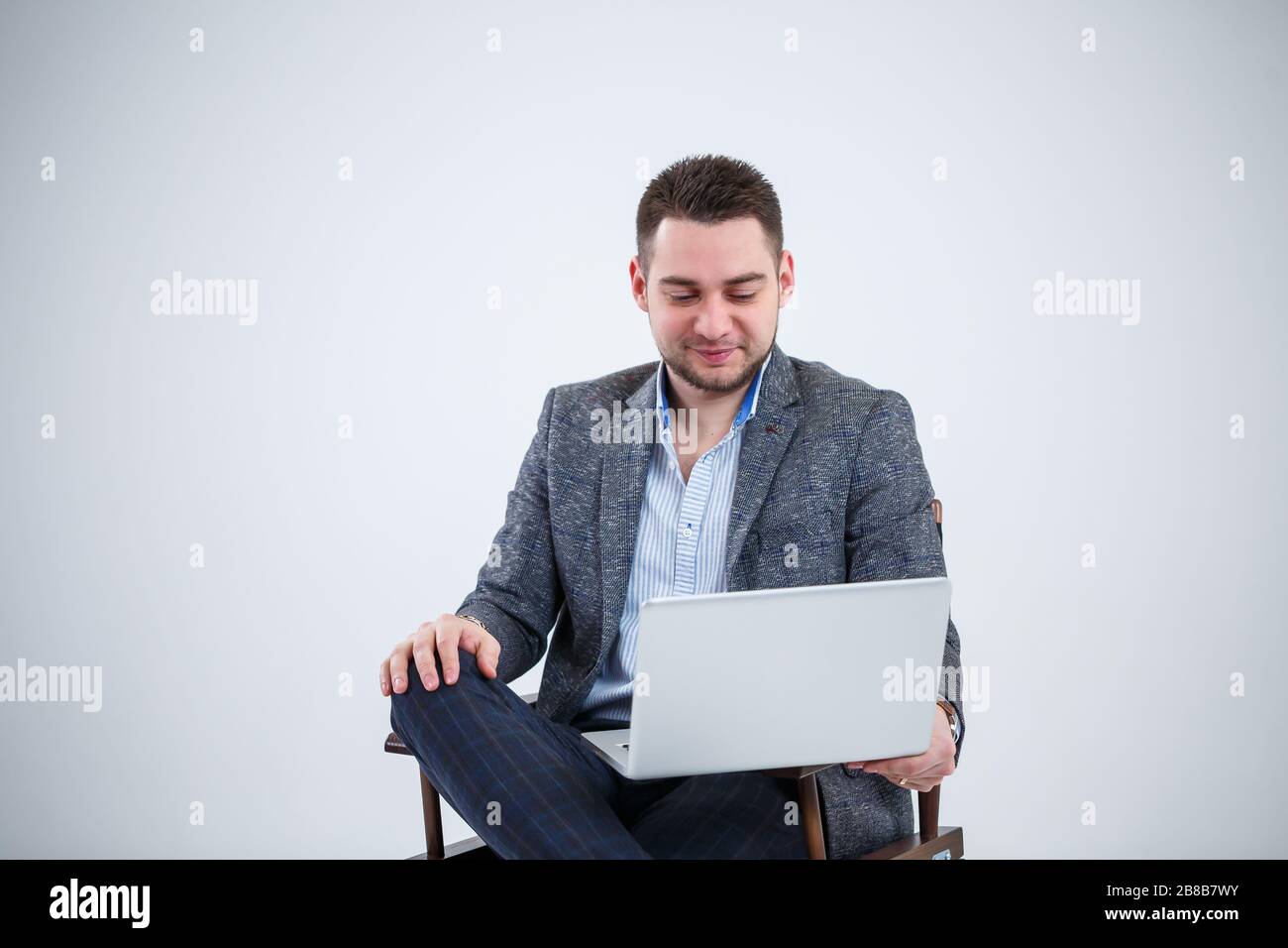 Male teacher director businessman sitting on a chair studying documents. He is looking at the laptop screen. New business project. Stock Photo
