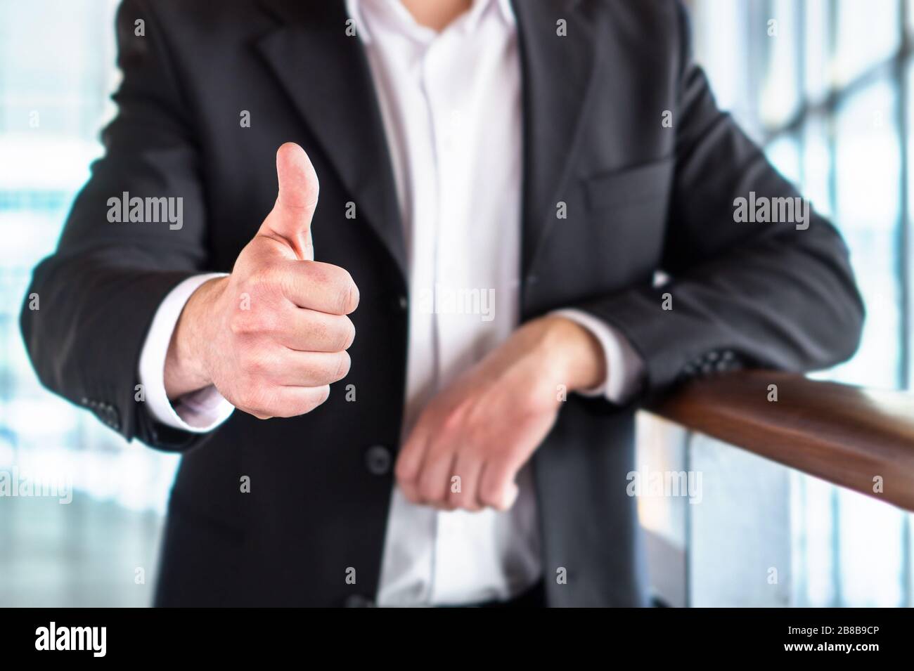 Business man or lawyer giving thumbs up in modern office building. Happy businessman showing satisfied and supportive hand gesture. Stock Photo