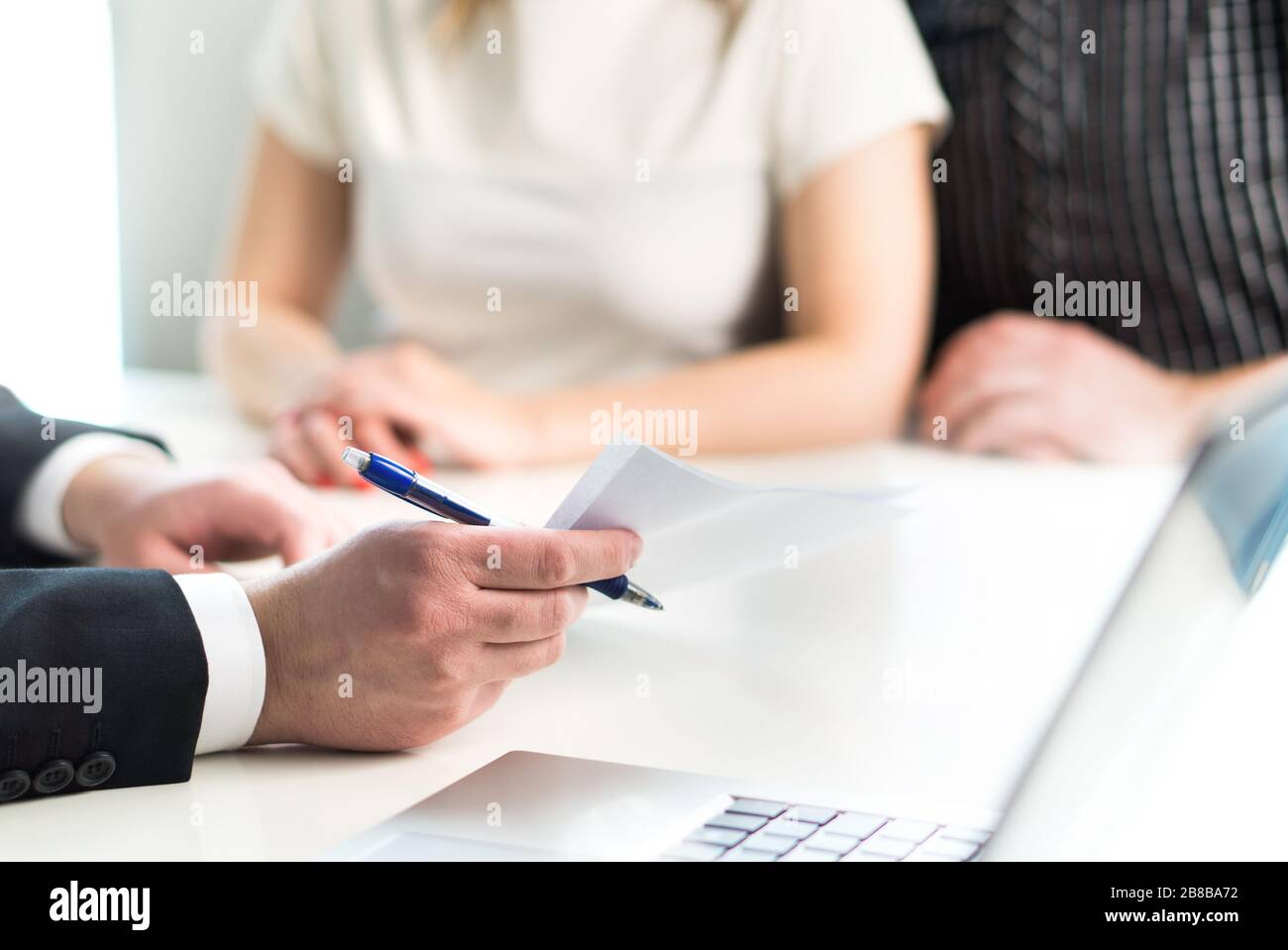Couple having meeting with legal advisor, real estate agent, businessman or banker. Lawyer giving advice or consultant showing document or agreement. Stock Photo