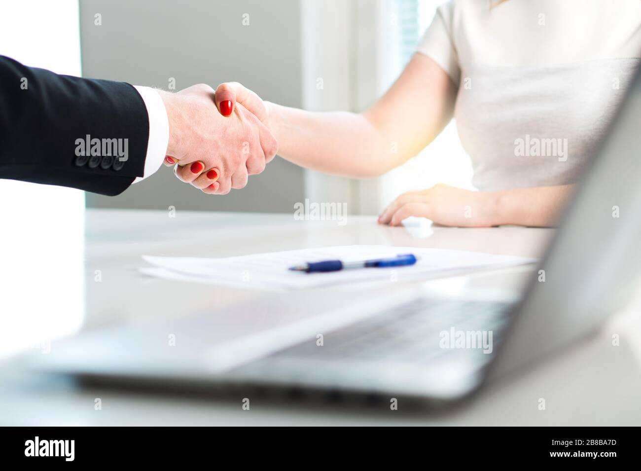 Business man and woman shaking hands after successful job interview or meeting. Young applicant making contract of employment. Stock Photo
