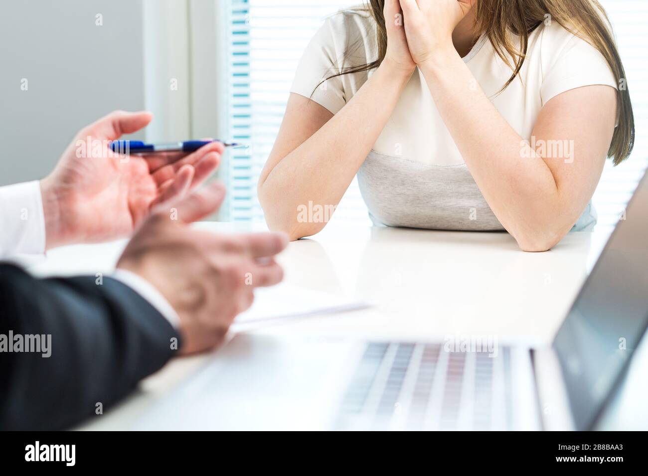 Young woman getting fired from work in office. Boss complaining or giving negative feedback to unhappy worker. Sad job applicant. Stock Photo