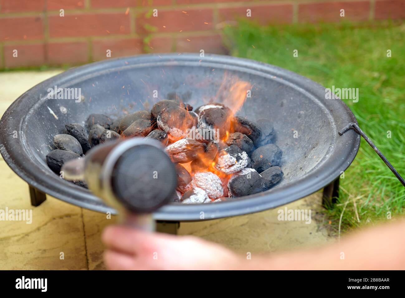 bbq grill charcoal starting fire with hair dryer in backyard in england