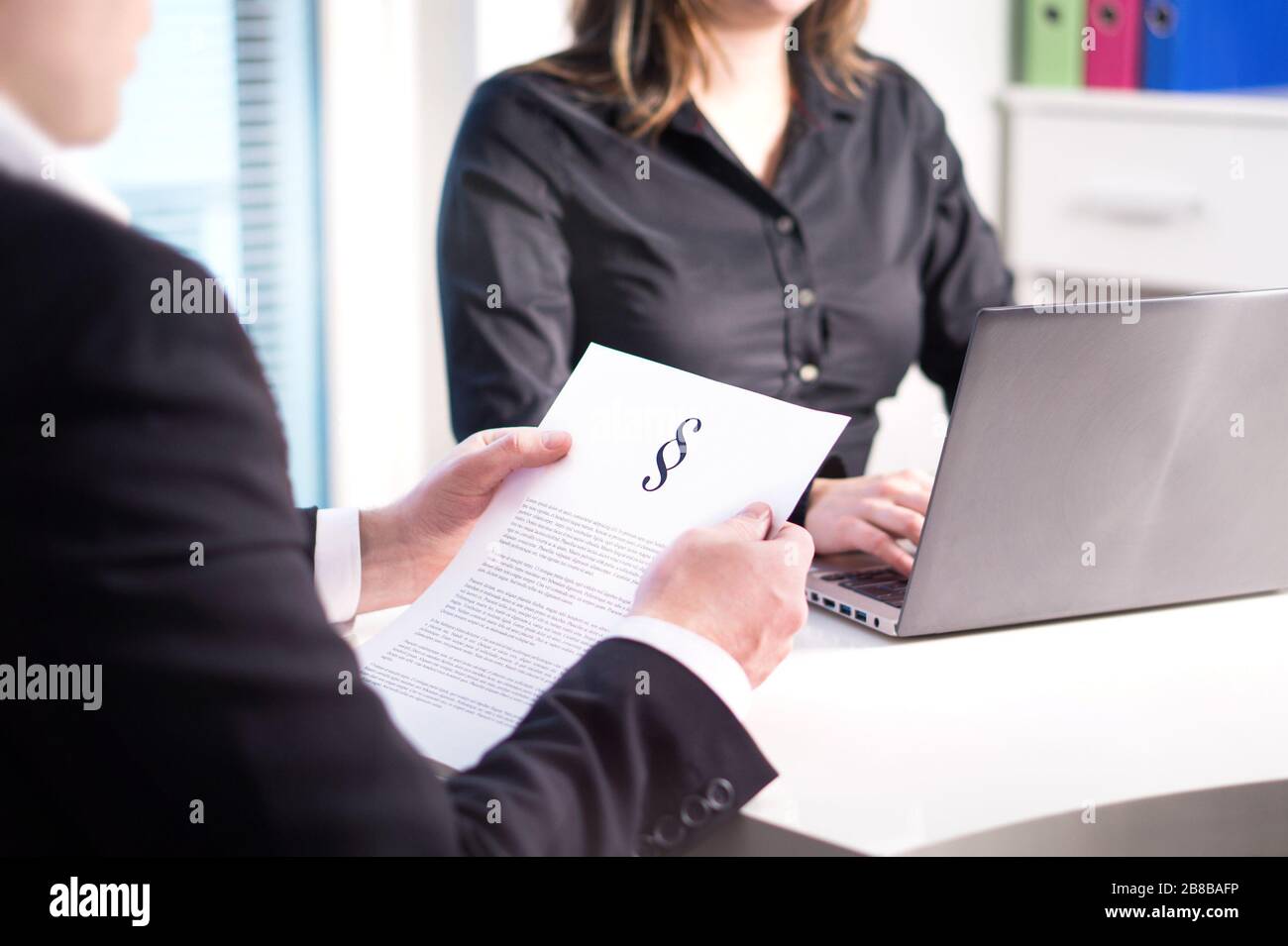 Two lawyers having meeting in office. Professional legal team and company working. Teamwork in law firm. Woman typing with laptop and man reading. Stock Photo