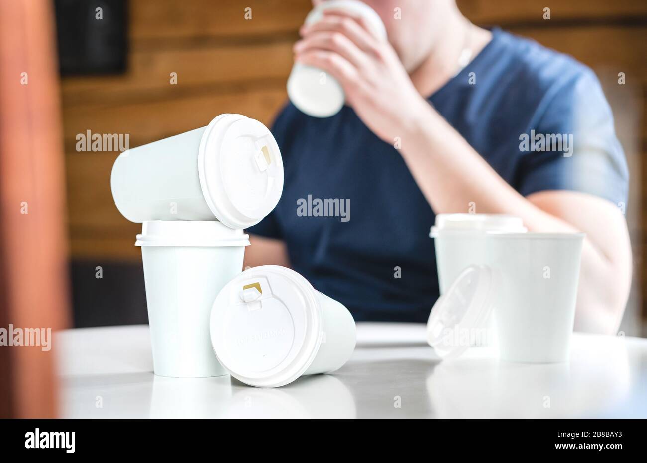 Coffee or caffeine addiction concept. Addicted or thirsty man drinking too much. Addict with many empty take away paper cups on table. Stock Photo