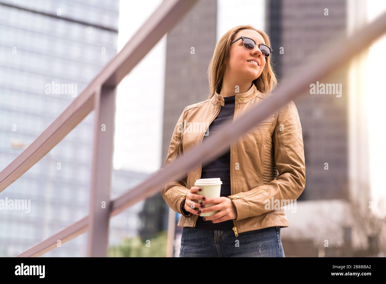 Happy relaxed woman enjoying take away cup of coffee in city street. Lady having coffee break in downtown. Tourist or business person. Stock Photo