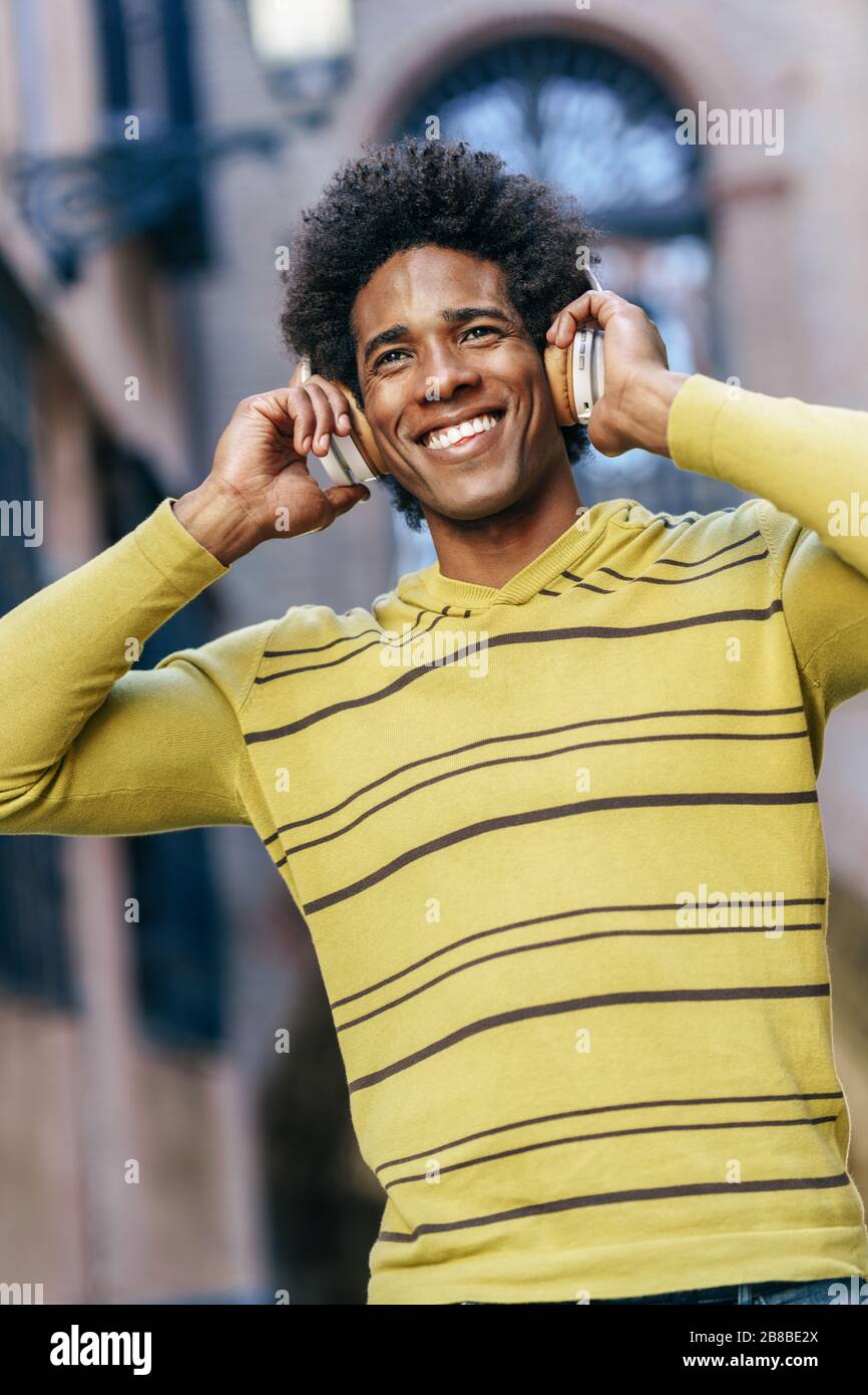Black man listening to music with wireless headphones sightseeing in Granada Stock Photo