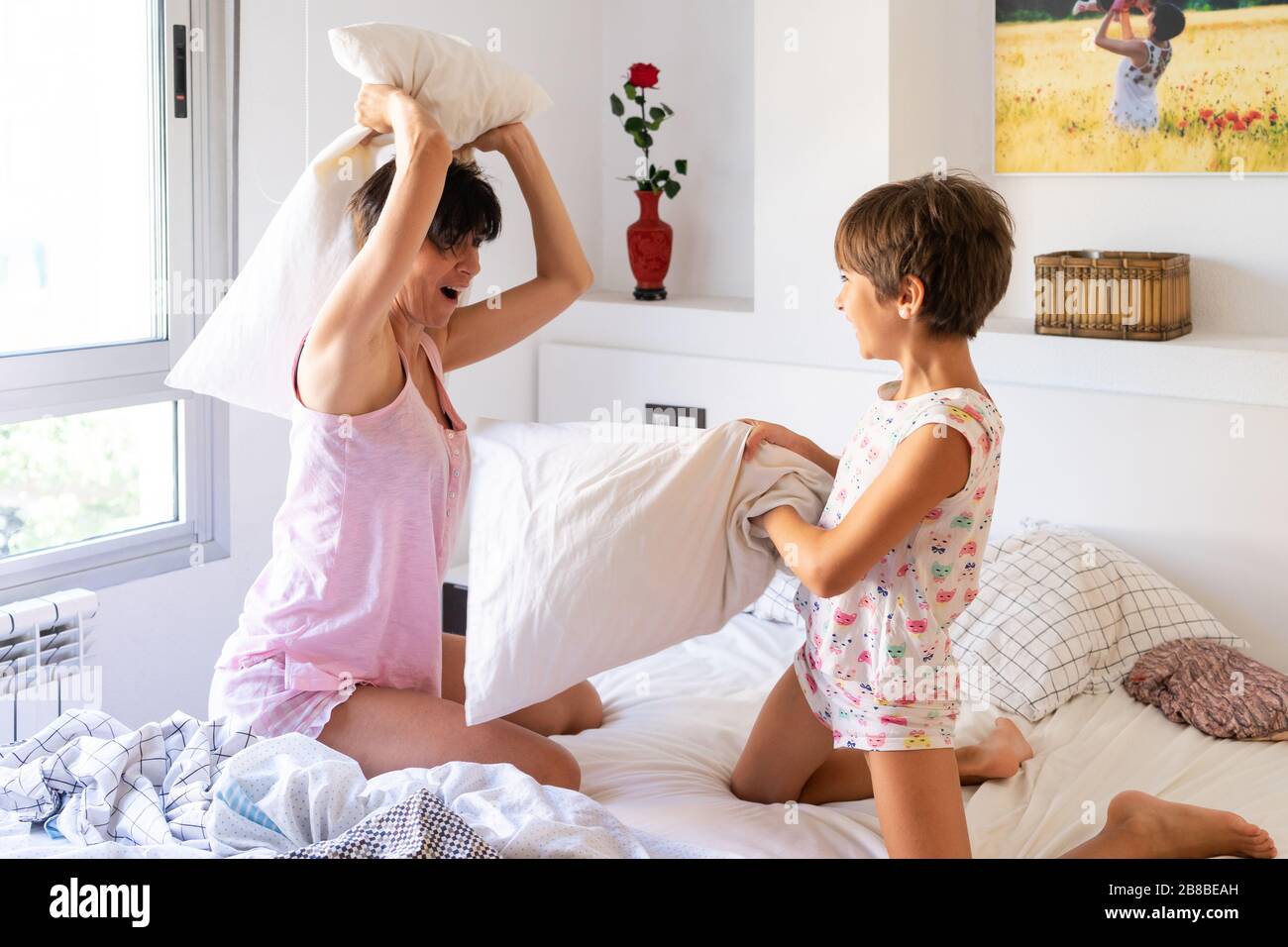 Mother and daughter having funny pillow fight on bed Stock Photo Alamy
