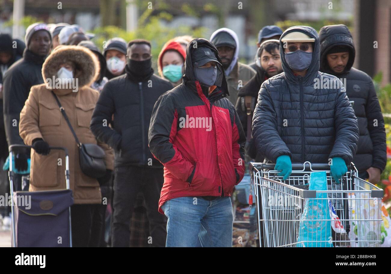 People queue outside a branch of Aldi in south London, a day after the Chancellor unveiled an emergency package aimed at protecting workers' jobs and wages as they face hardship in the fight against the coronavirus pandemic. Stock Photo