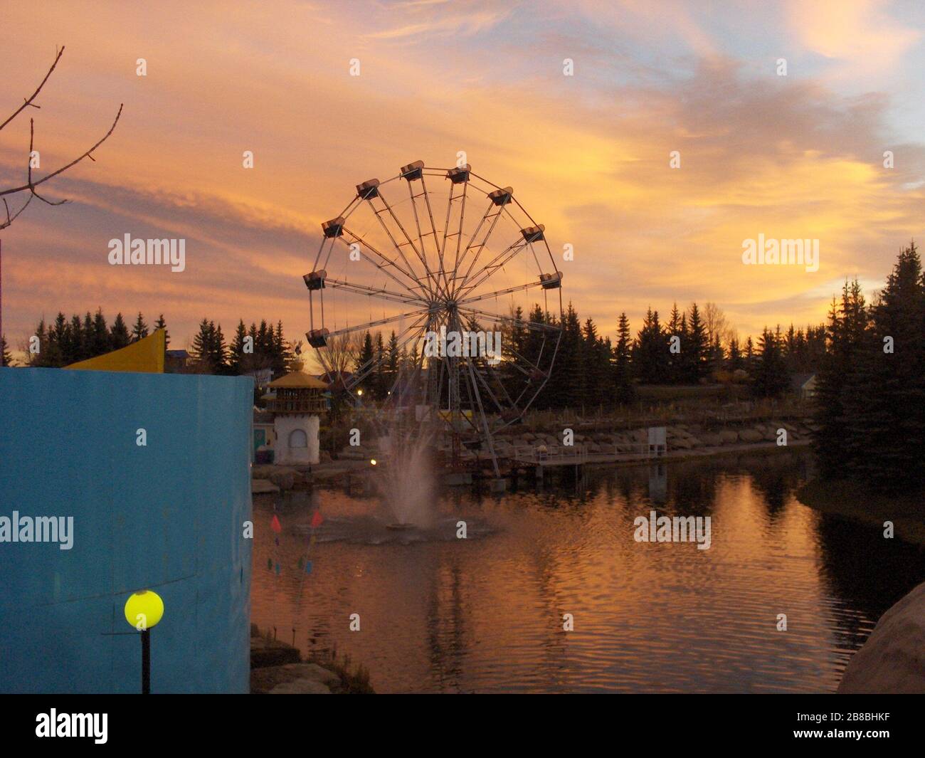 'English: Calaway Park (Calgary, Canada) - Big Eli (Calaway's name for their Ferris Wheel) in front of a sunset. Also shown are the Twiz and Twirl Maze (left) and Mulligan’s Island Mini Golf (immediate left of Big Eli).; 9 October 2006; Picture shot by employee (ride operator) of Calaway; Jonathan Verge; ' Stock Photo