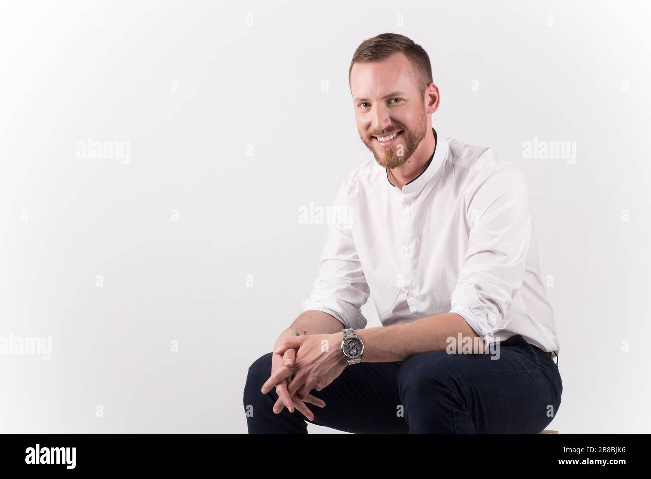 A young handsome male sitting and posing isolated on white background Stock Photo