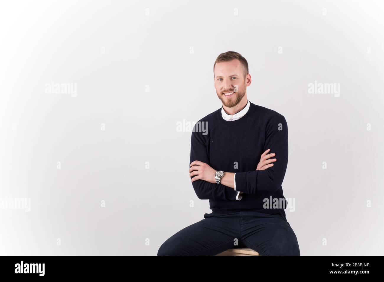 A young handsome male sitting and posing isolated on white background Stock Photo