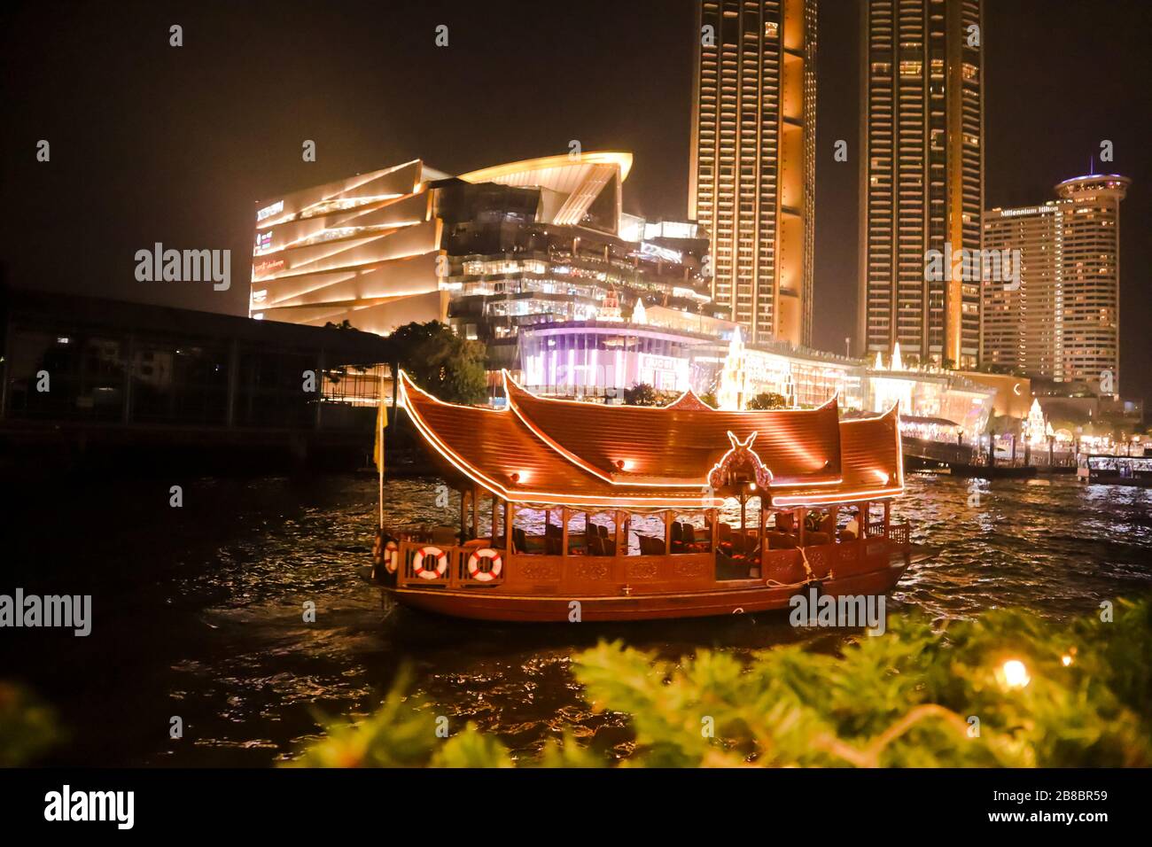 Night photo of Bangkok and a travel boat sailing in a river. Stock Photo