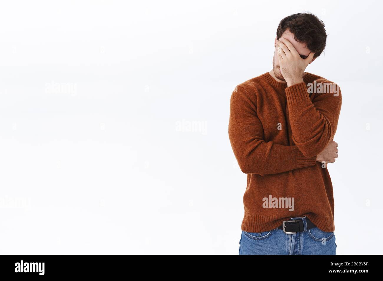 Embarrassed and bothered young man fed up, tired of having this useless conversation, make facepalm gesture and standing white background annoyed Stock Photo
