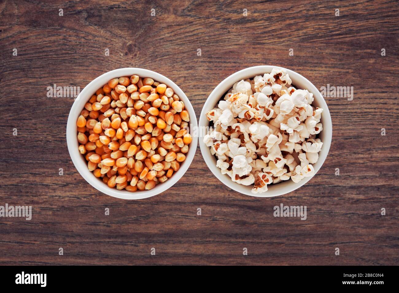 Two bowls filled with popcorn and corn maize or kernel seed. Popcorn preparation. Stock Photo