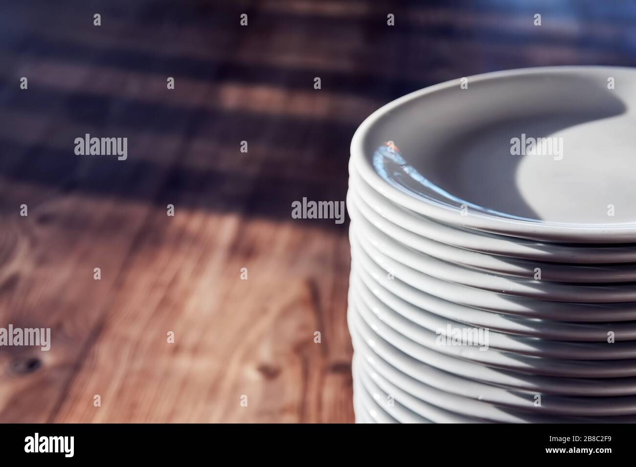 Pile of white plates on the wooden table of a restaurant or cafe under ...