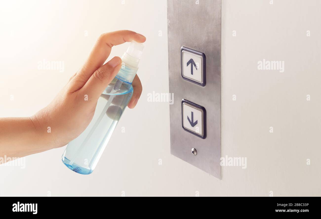 disinfect, sanitize, hygiene care. people using alcohol spray on elevator button and frequently touched area for cleaning and disinfection, prevention Stock Photo