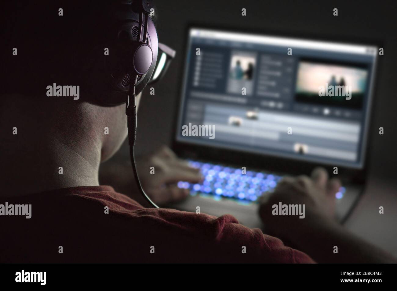 Video editing with laptop. Professional editor adding special effects or color grading footage. Back view of young man using computer software. Stock Photo