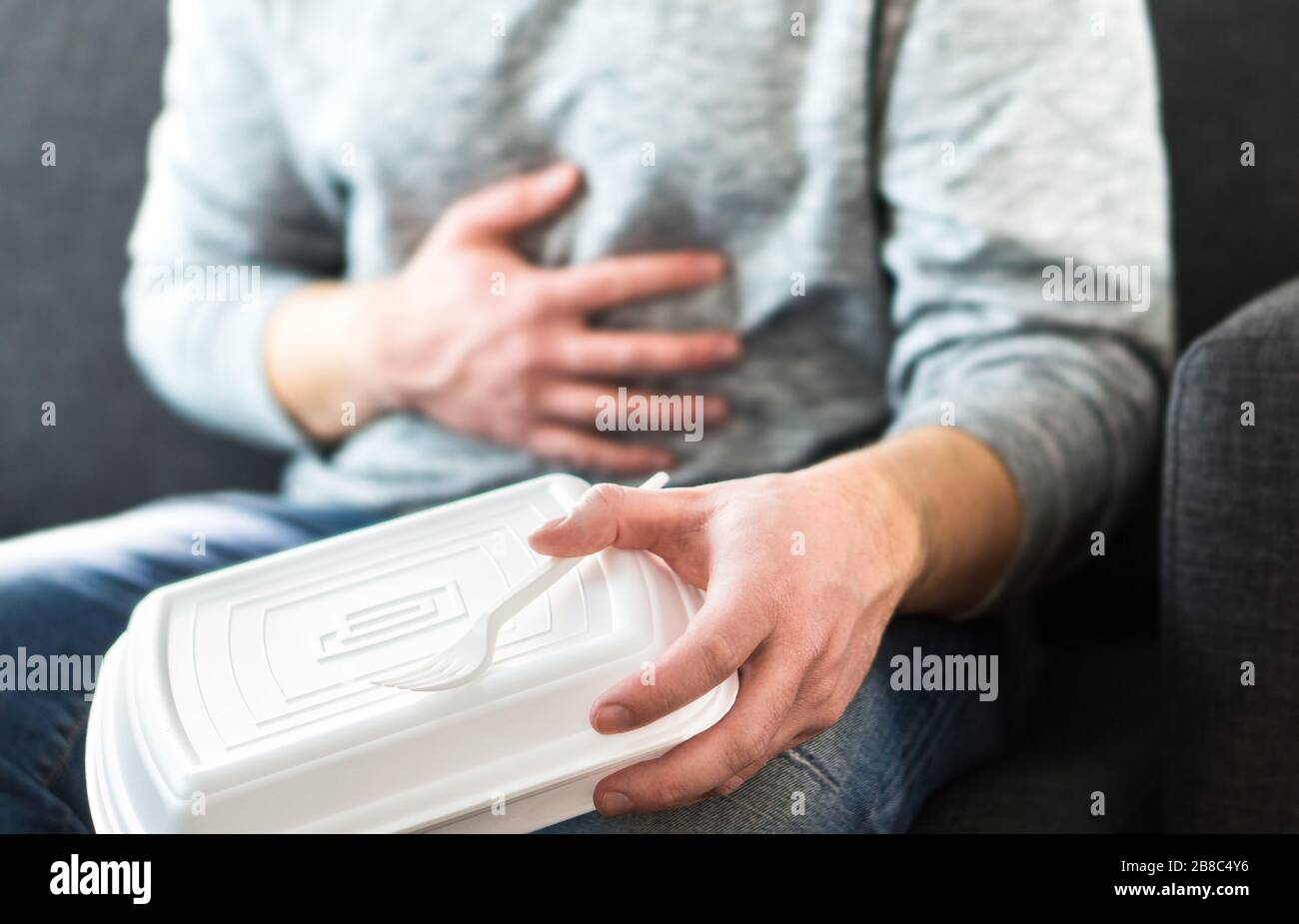Man having diarrhea or food poisoning after unhealthy junk fast food. Guy has to go to toilet after eating too much. Stomach pain, digestion problem. Stock Photo