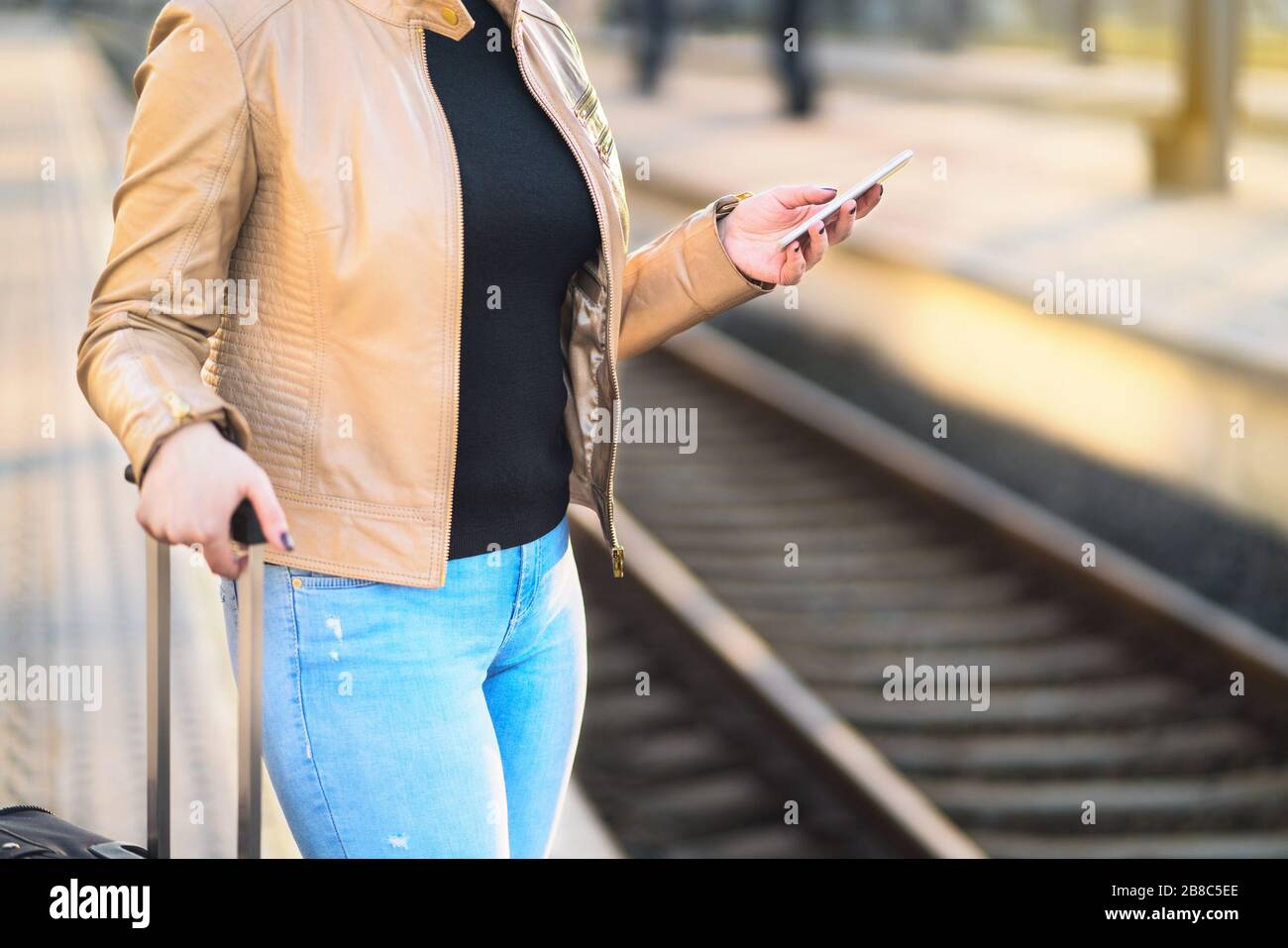 Commuter using smartphone in train station. Woman buying electronic ticket with mobile phone in platform. Commute, transportation and technology. Stock Photo