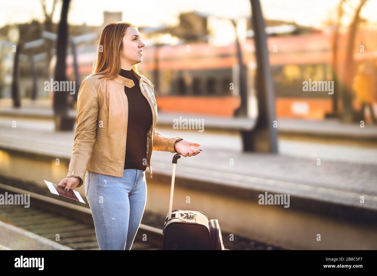 Frustrated woman at train station. Late, delayed, canceled or behind schedule. Unhappy and sad passenger lost in wrong platform. Stock Photo