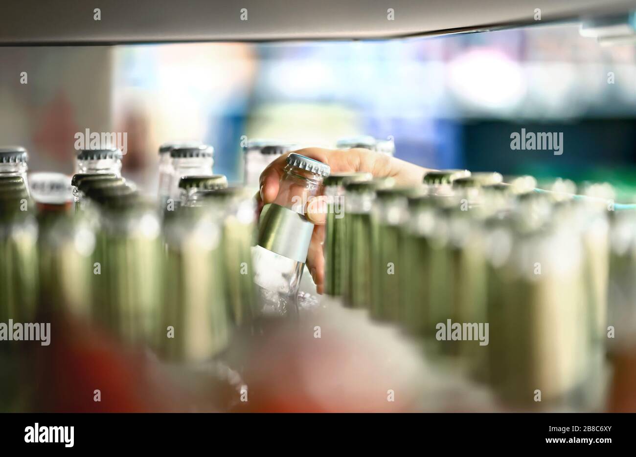 Close up of drink shelf in supermarket. Alcohol, soda, sodapop, mineral water or ginger ale bottle. Customer buying product in grocery store. Stock Photo