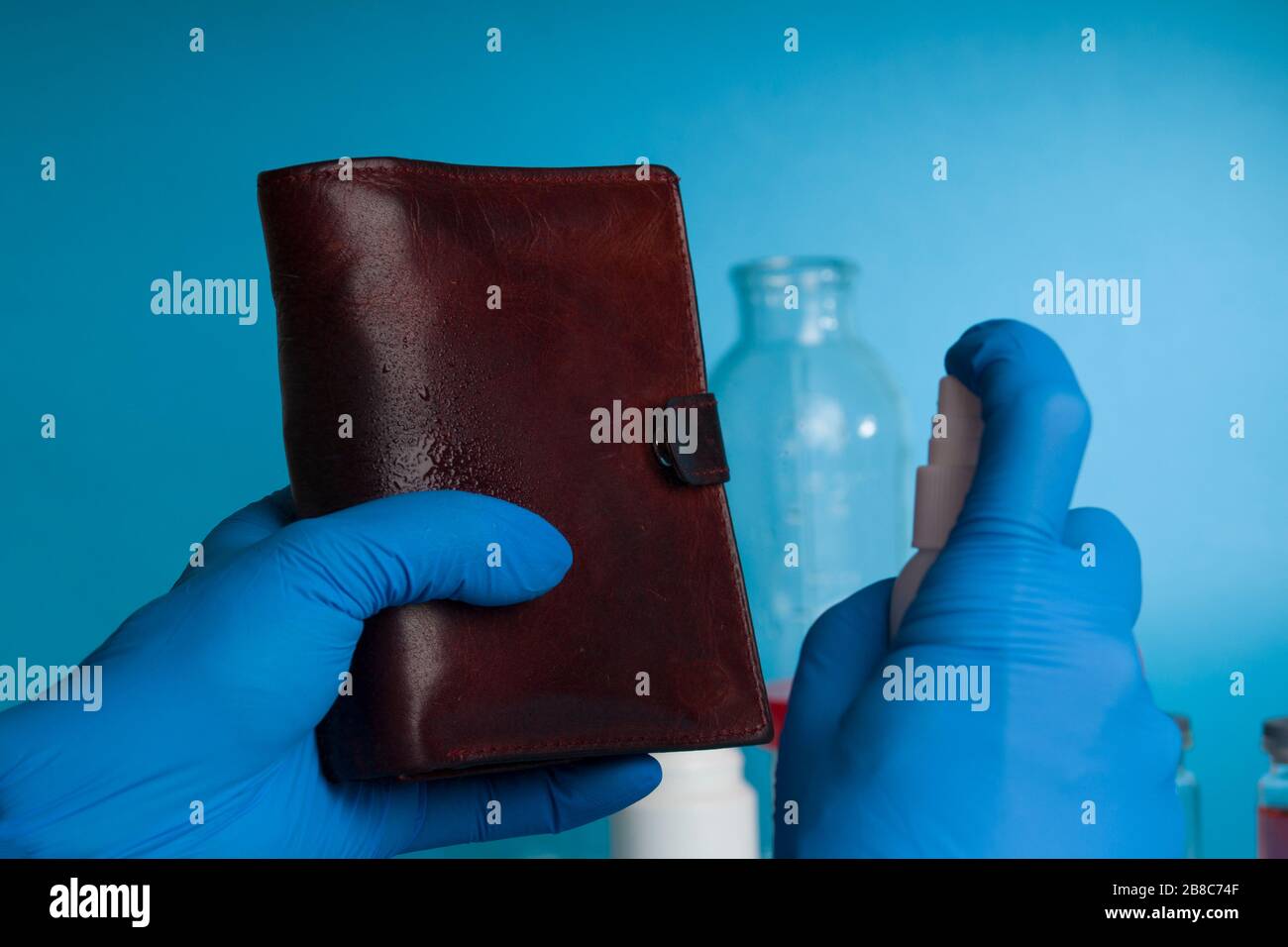 Concept of Cleaning personal belongings for disease prevention from Coronavirus. cleaning leather wallet with antiseptic spray Stock Photo