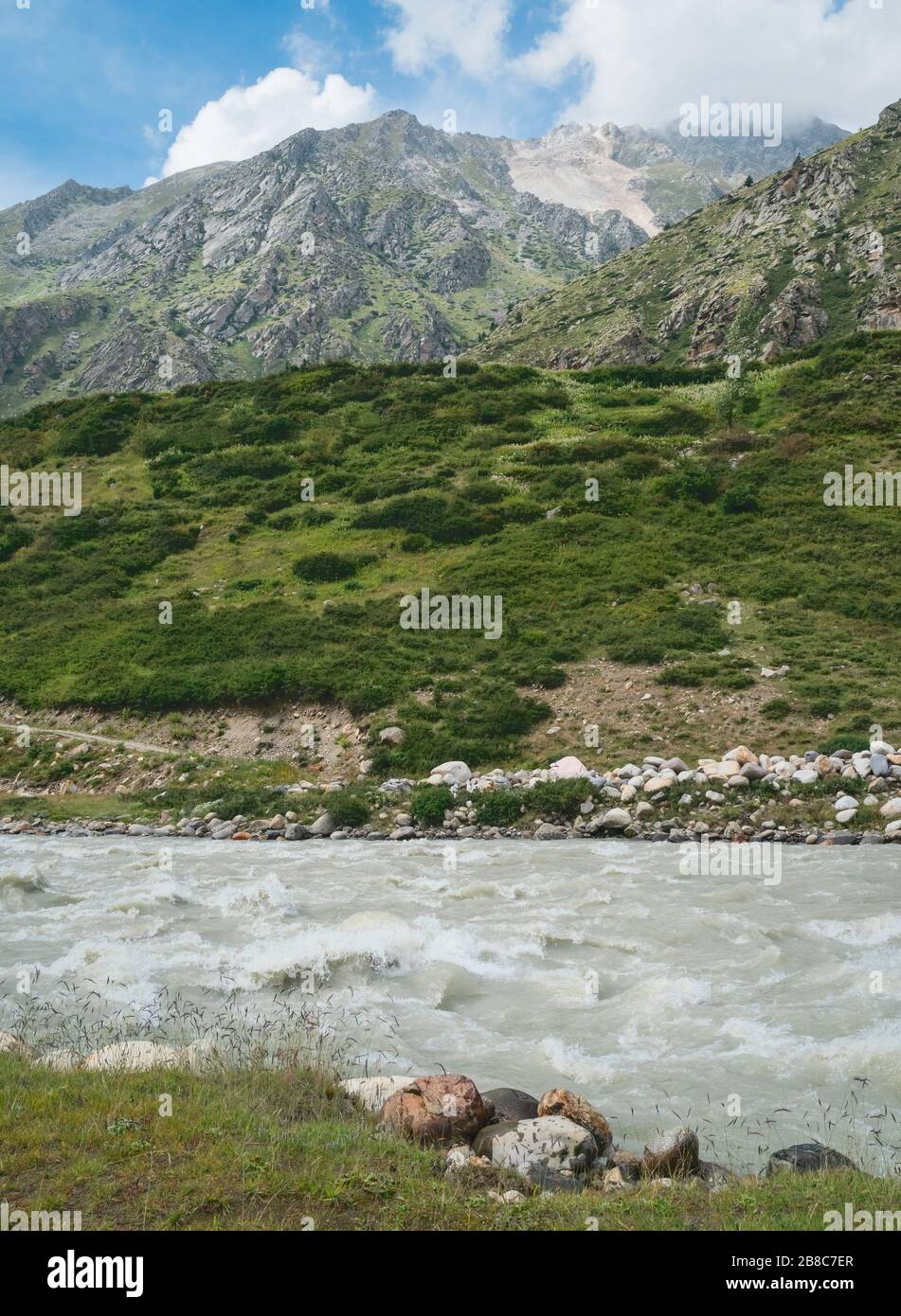 View across the Baspa river towards the Himalayas and rugged, rocky slopes under blue sky in summer near Chitkul, Himachal Pradesh, India. Stock Photo
