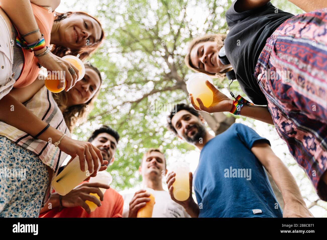 group of young people from different ethnic groups standing in a circle on the street with a juice in a plastic container on a sunny day Stock Photo