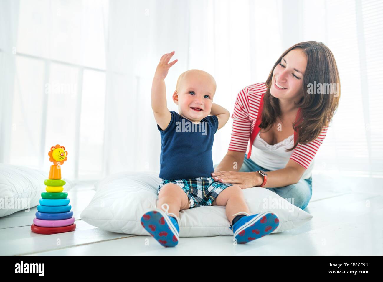 Charming cute cheerful boy with a happy caring mom at home in a bright ...